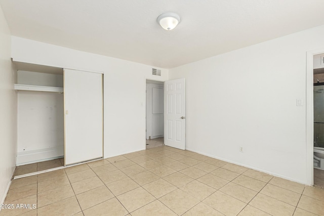 unfurnished bedroom with a closet, light tile patterned flooring, visible vents, and baseboards