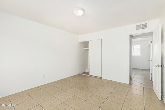 unfurnished bedroom with light tile patterned floors, visible vents, and a closet