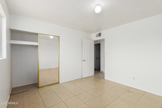 unfurnished bedroom featuring light tile patterned floors, visible vents, and a closet