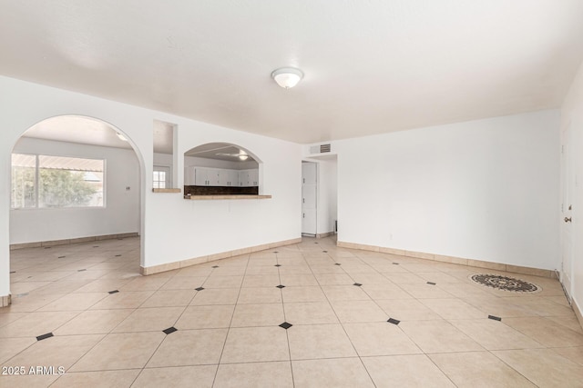 spare room featuring light tile patterned floors, visible vents, and baseboards