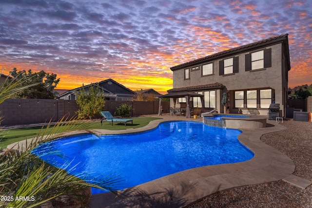 pool at dusk featuring an in ground hot tub, a patio area, and a grill