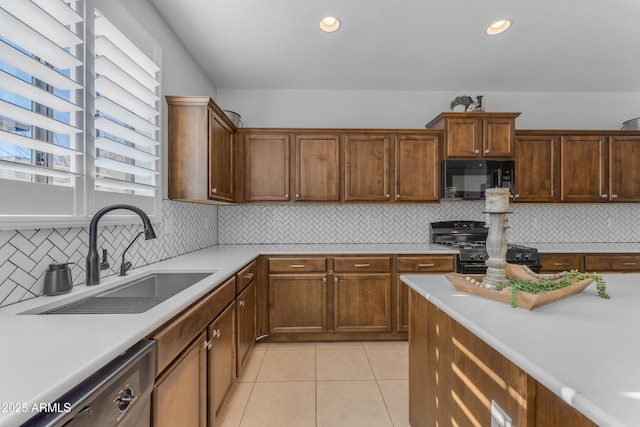 kitchen featuring sink, light tile patterned flooring, black appliances, and plenty of natural light