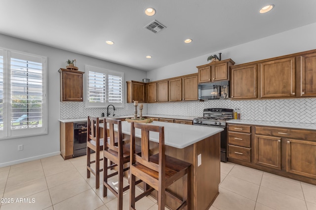 kitchen with a kitchen breakfast bar, tasteful backsplash, black appliances, light tile patterned floors, and a center island