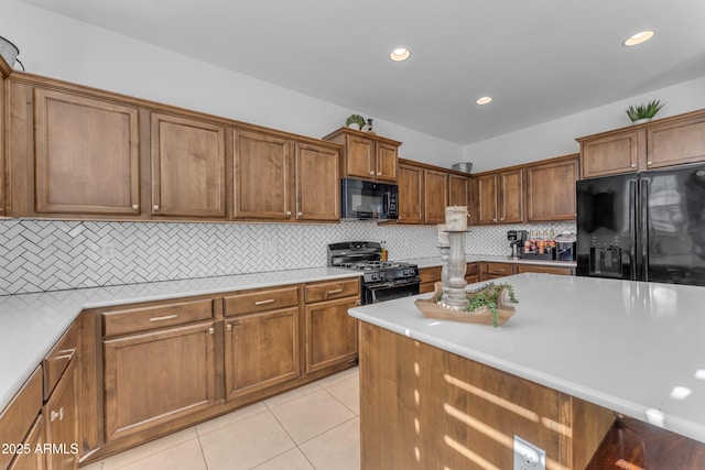 kitchen with tasteful backsplash, light tile patterned floors, and black appliances