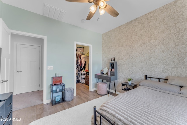 bedroom with ceiling fan, light wood-type flooring, a spacious closet, and a closet