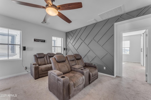 carpeted cinema room with ceiling fan and a healthy amount of sunlight