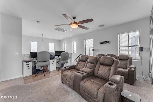 home theater room with light colored carpet, plenty of natural light, and ceiling fan