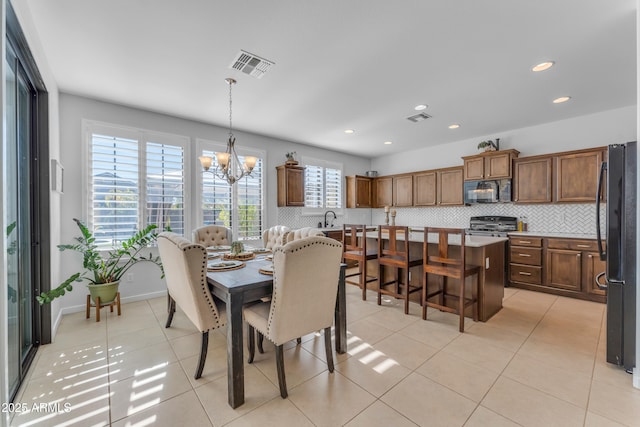 tiled dining room with an inviting chandelier, plenty of natural light, and sink