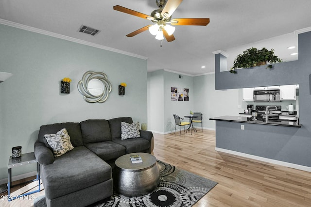 living room with light hardwood / wood-style flooring, ceiling fan, ornamental molding, and sink