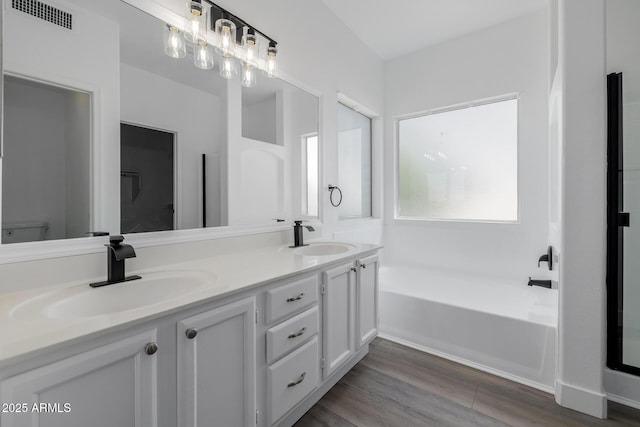 8478 W Grovers Ave, Peoria, AZ 85382 - bathroom featuring a garden tub, double vanity, and wood finished floors