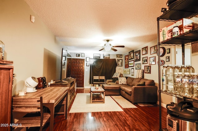 living room featuring ceiling fan, hardwood / wood-style flooring, and a textured ceiling