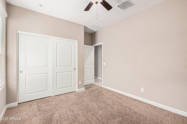 unfurnished bedroom featuring light colored carpet, ceiling fan, and a closet