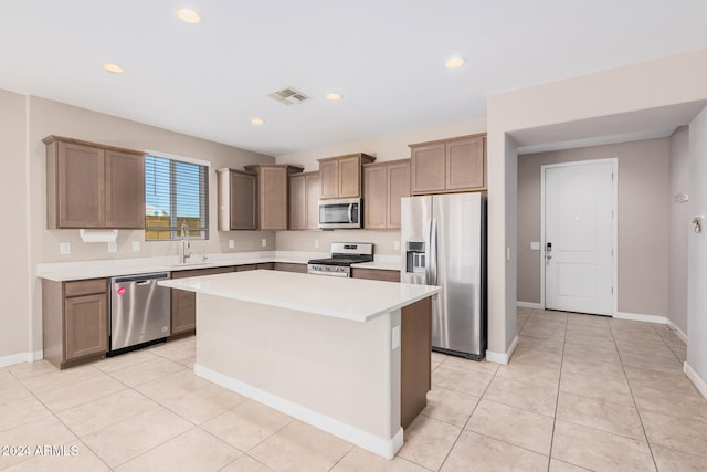 kitchen featuring light tile patterned flooring, sink, appliances with stainless steel finishes, and a center island