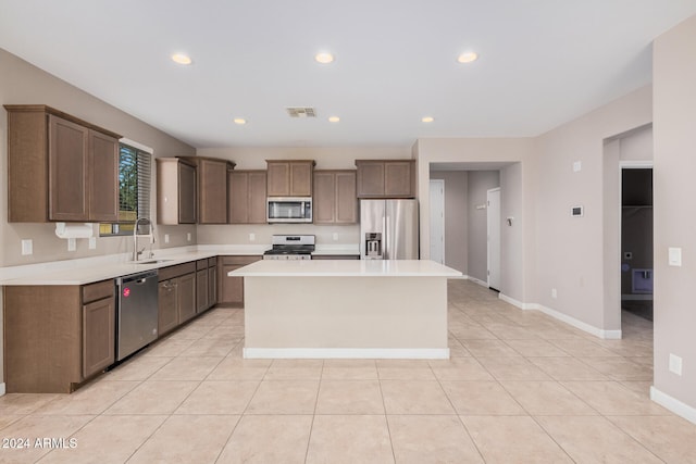 kitchen featuring a kitchen island, sink, light tile patterned floors, and stainless steel appliances