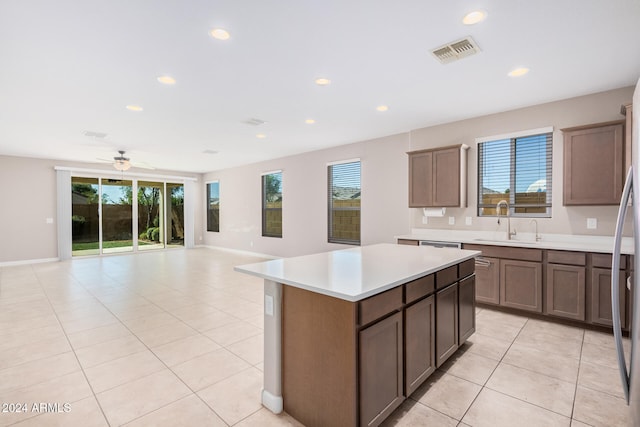 kitchen with light tile patterned flooring, a kitchen island, sink, and ceiling fan