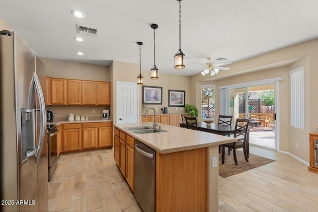 kitchen with visible vents, stainless steel appliances, light countertops, light wood-type flooring, and a sink