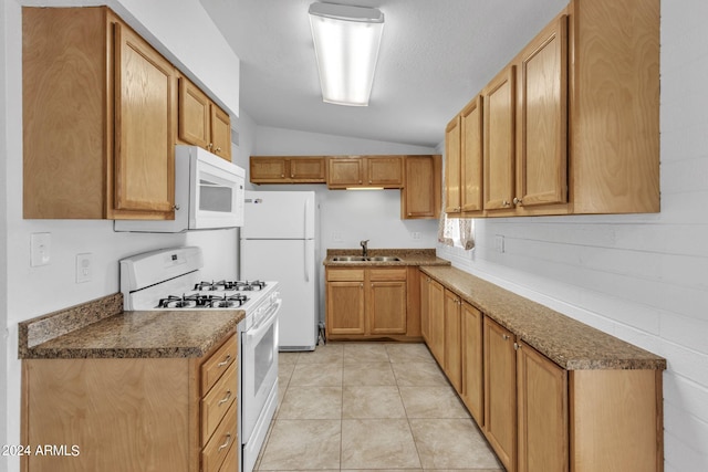 kitchen with white appliances, dark countertops, lofted ceiling, a sink, and light tile patterned flooring