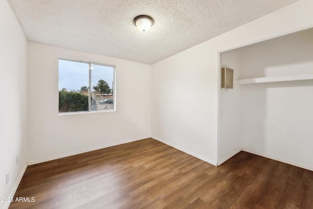 empty room with wood-type flooring and a textured ceiling