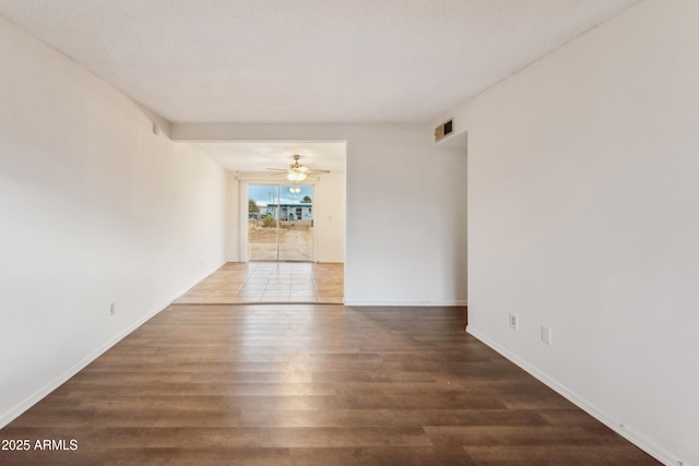 empty room with dark wood-type flooring and ceiling fan