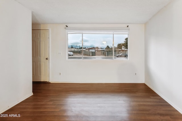 spare room with dark hardwood / wood-style floors and a textured ceiling