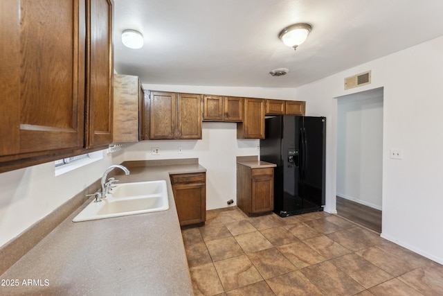 kitchen with sink and black refrigerator with ice dispenser