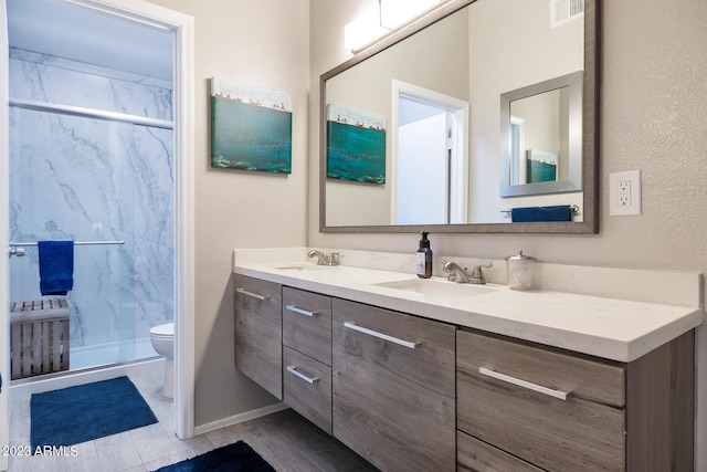 bathroom with an enclosed shower, double sink, large vanity, and toilet