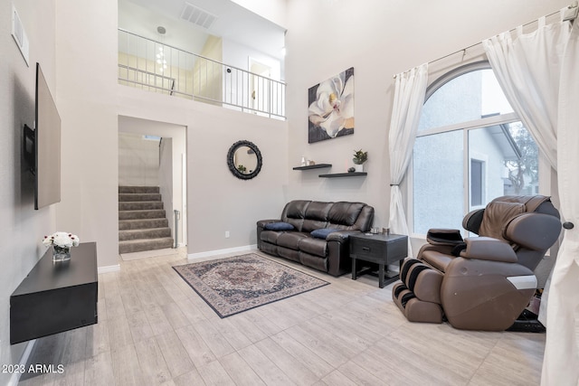 living room with light wood-type flooring and a high ceiling