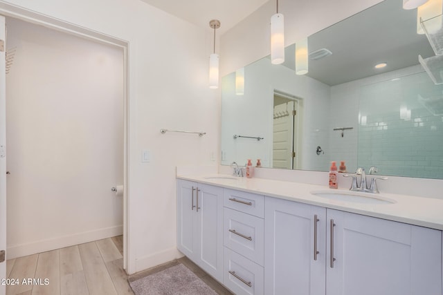 bathroom featuring wood-type flooring, vanity, and tiled shower