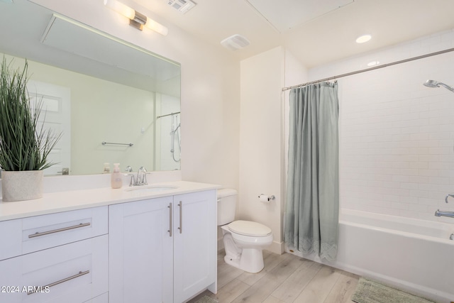 full bathroom featuring hardwood / wood-style floors, shower / bath combo, vanity, and toilet