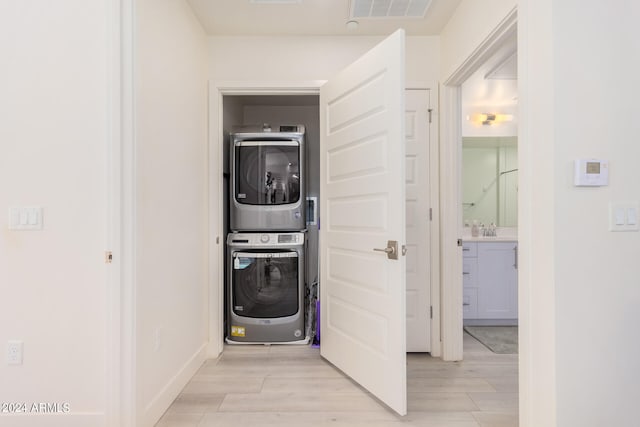 washroom featuring stacked washer / drying machine, sink, and light hardwood / wood-style flooring