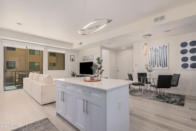 kitchen with pendant lighting, white cabinets, a kitchen island, and light wood-type flooring