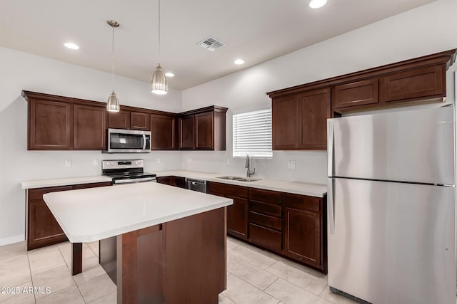 2000 N 36th St Unit 10, Phoenix, AZ 85008 - kitchen featuring appliances with stainless steel finishes, dark brown cabinets, light countertops, light tile patterned floors, and a center island
