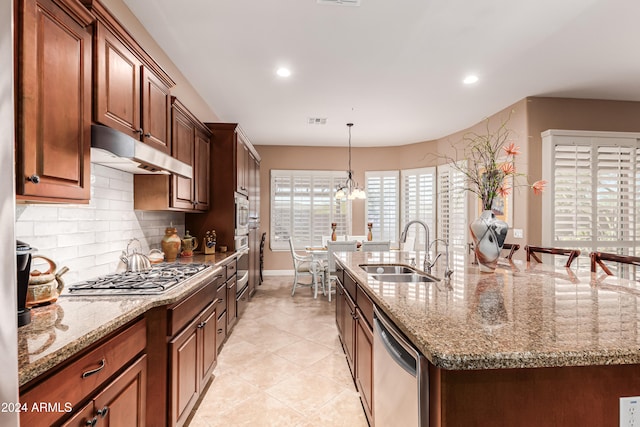 kitchen featuring stainless steel appliances, a healthy amount of sunlight, sink, and an island with sink