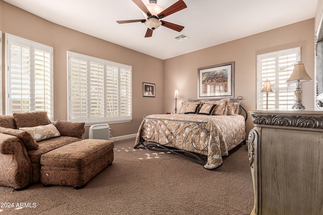 carpeted bedroom featuring multiple windows and ceiling fan