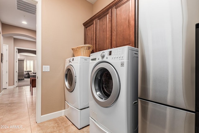 clothes washing area featuring cabinets, independent washer and dryer, and light tile patterned floors