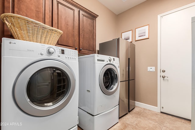 laundry room with cabinets, light tile patterned floors, and independent washer and dryer