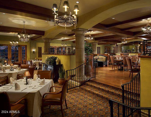 dining room featuring decorative columns, hardwood / wood-style flooring, and beamed ceiling