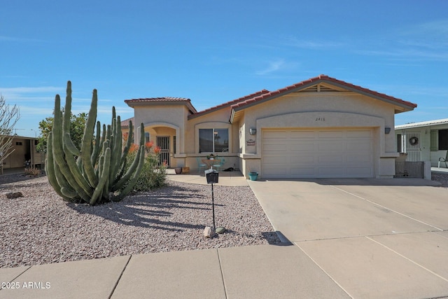 view of front of house with driveway, a tiled roof, an attached garage, and stucco siding