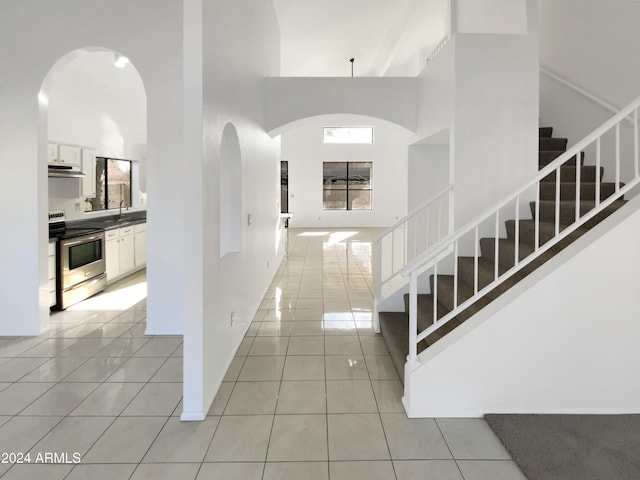 staircase with tile patterned floors, sink, and a high ceiling