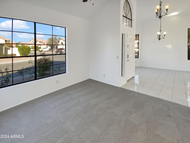 empty room with a high ceiling, a notable chandelier, and light tile patterned flooring