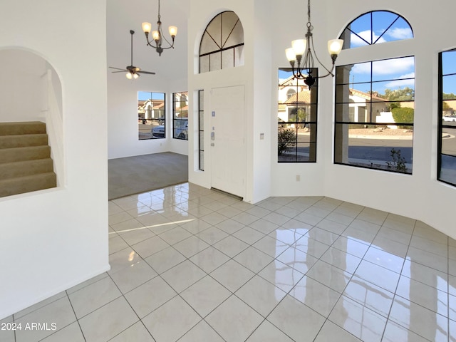 interior space featuring a high ceiling and ceiling fan with notable chandelier