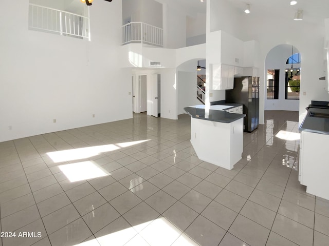 kitchen featuring kitchen peninsula, a breakfast bar, light tile patterned floors, white cabinets, and a high ceiling