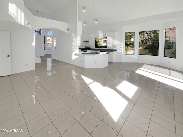 unfurnished living room with light tile patterned flooring and high vaulted ceiling