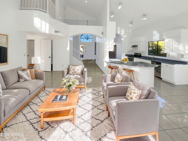 living room with light tile patterned flooring, sink, and high vaulted ceiling