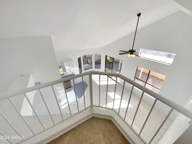 stairway with ceiling fan, carpet floors, and a towering ceiling