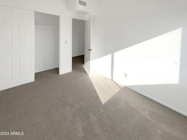 unfurnished bedroom featuring a closet and dark colored carpet