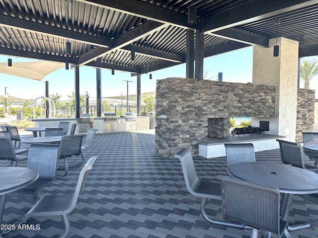 view of patio / terrace with an outdoor stone fireplace, exterior kitchen, outdoor dining space, and grilling area