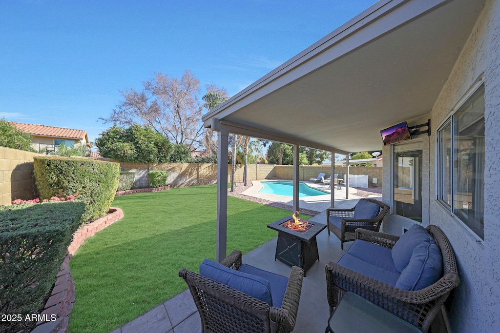 view of yard featuring a fenced in pool, a fire pit, and a patio area