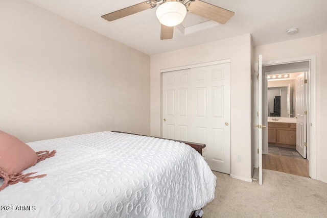 bedroom featuring ensuite bath, light carpet, a closet, and ceiling fan