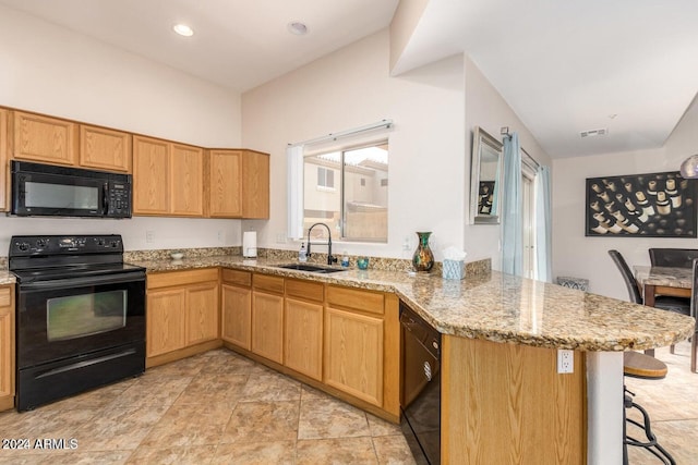 kitchen featuring black appliances, sink, a kitchen bar, kitchen peninsula, and light stone counters